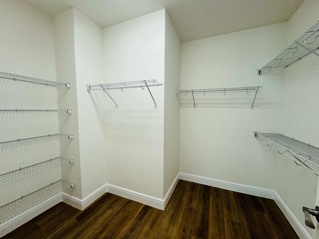 a walk in closet with shelves and a wood floor