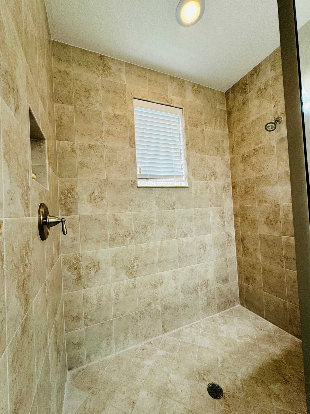 a tiled shower in a bathroom with a window