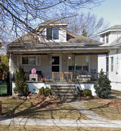 a white house with a porch and a pink chair