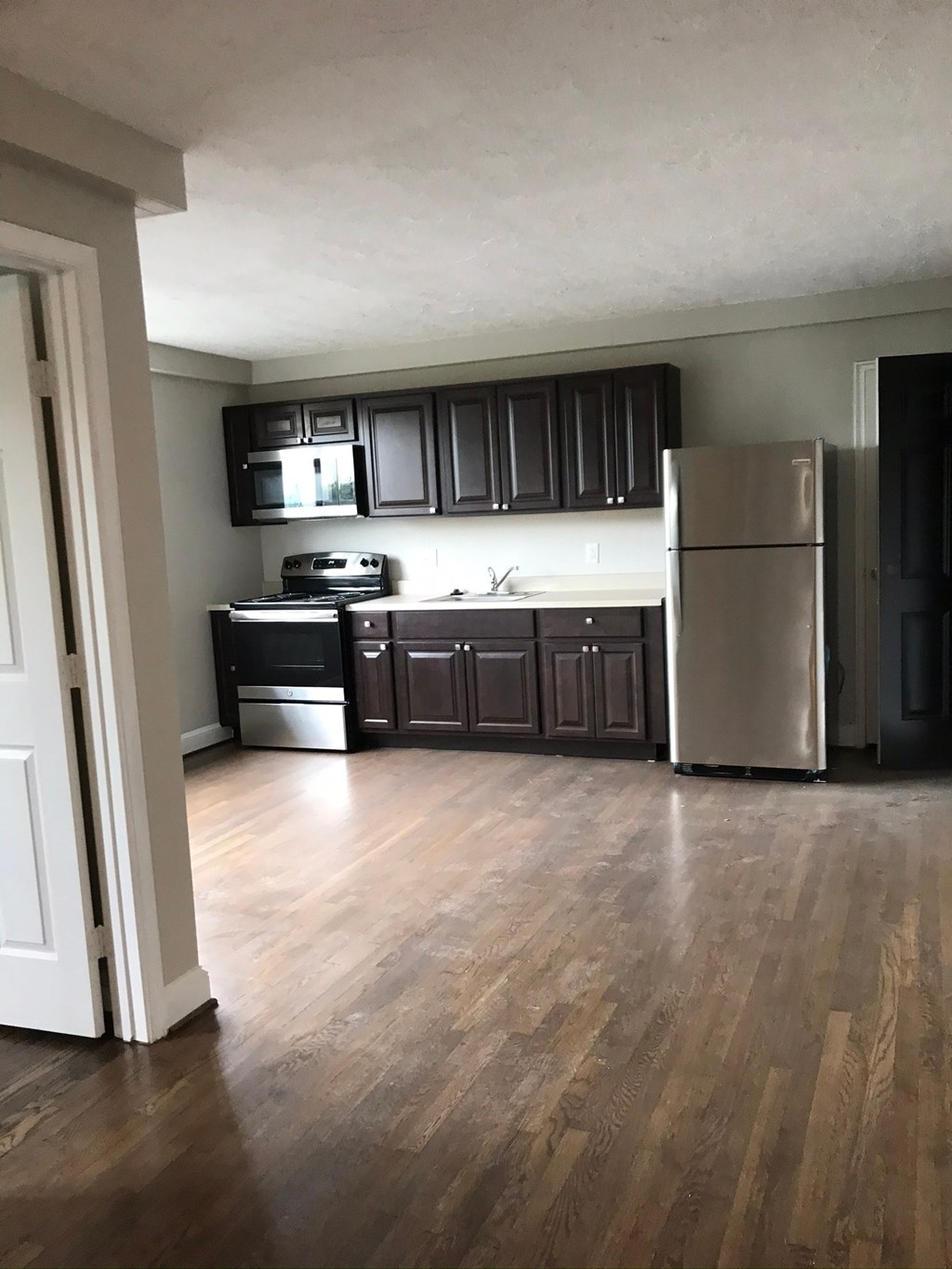 an empty kitchen with wooden floors and black cabinets