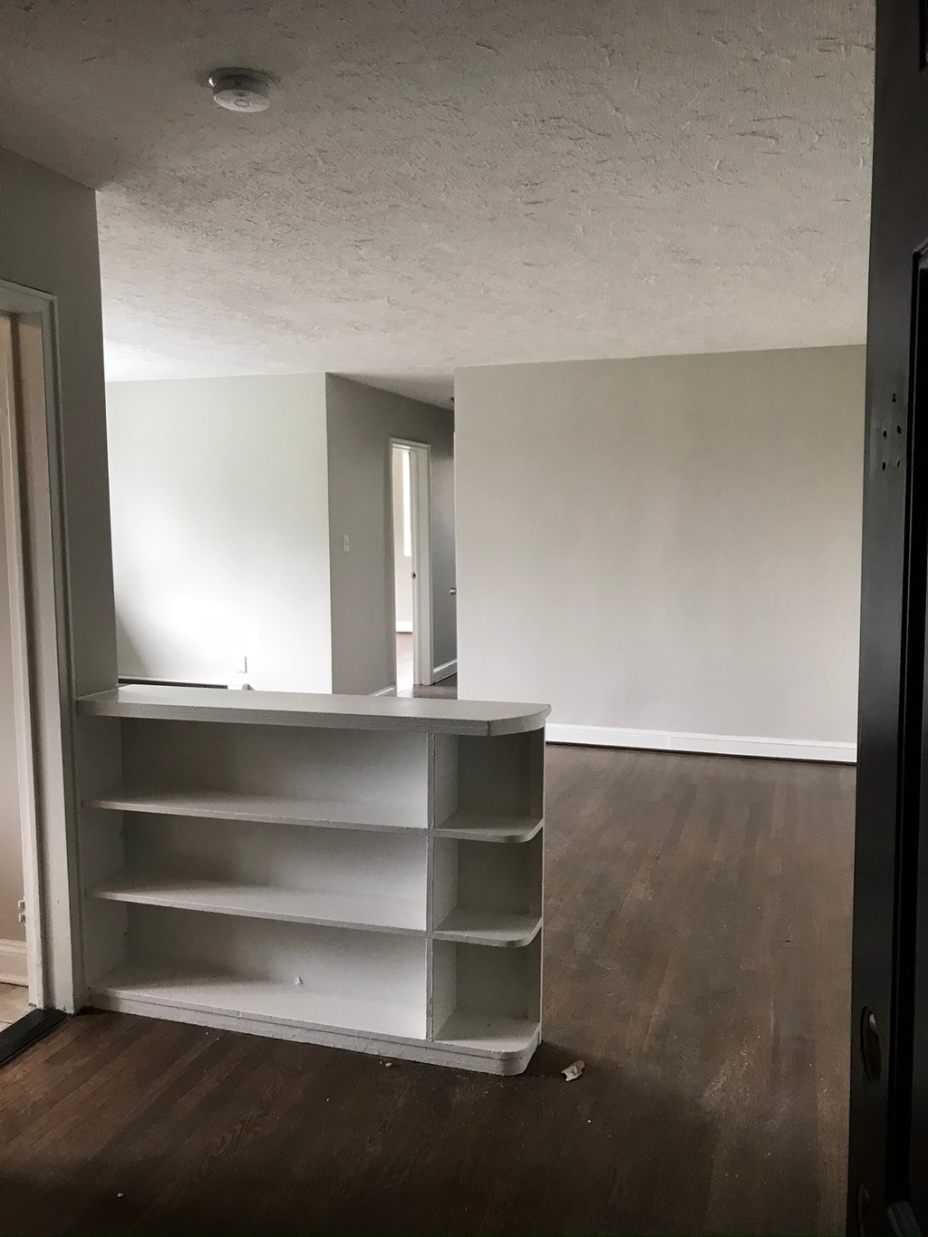 an empty room with white shelves and a door