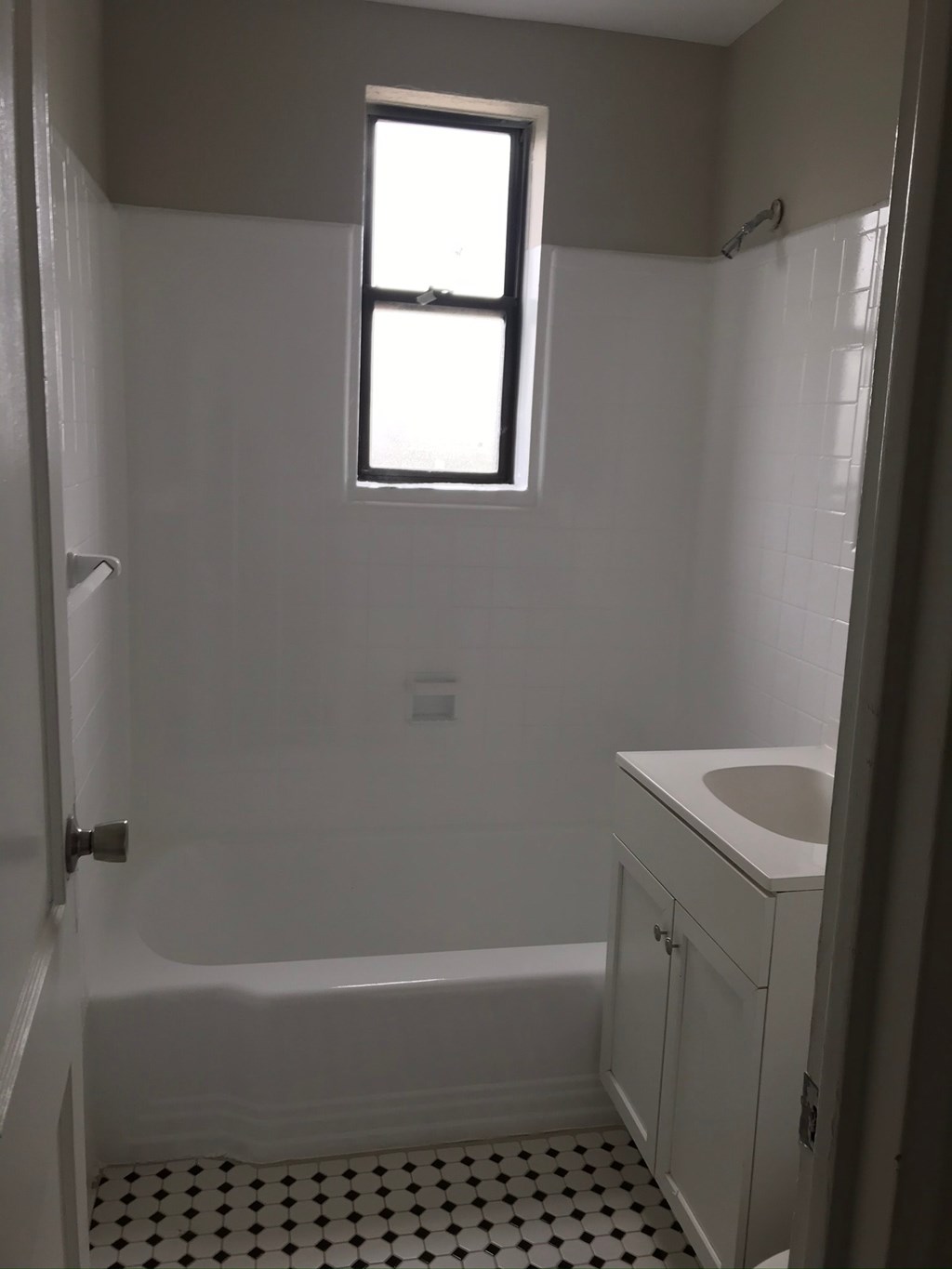 a white bathroom with a sink and a tub and a window