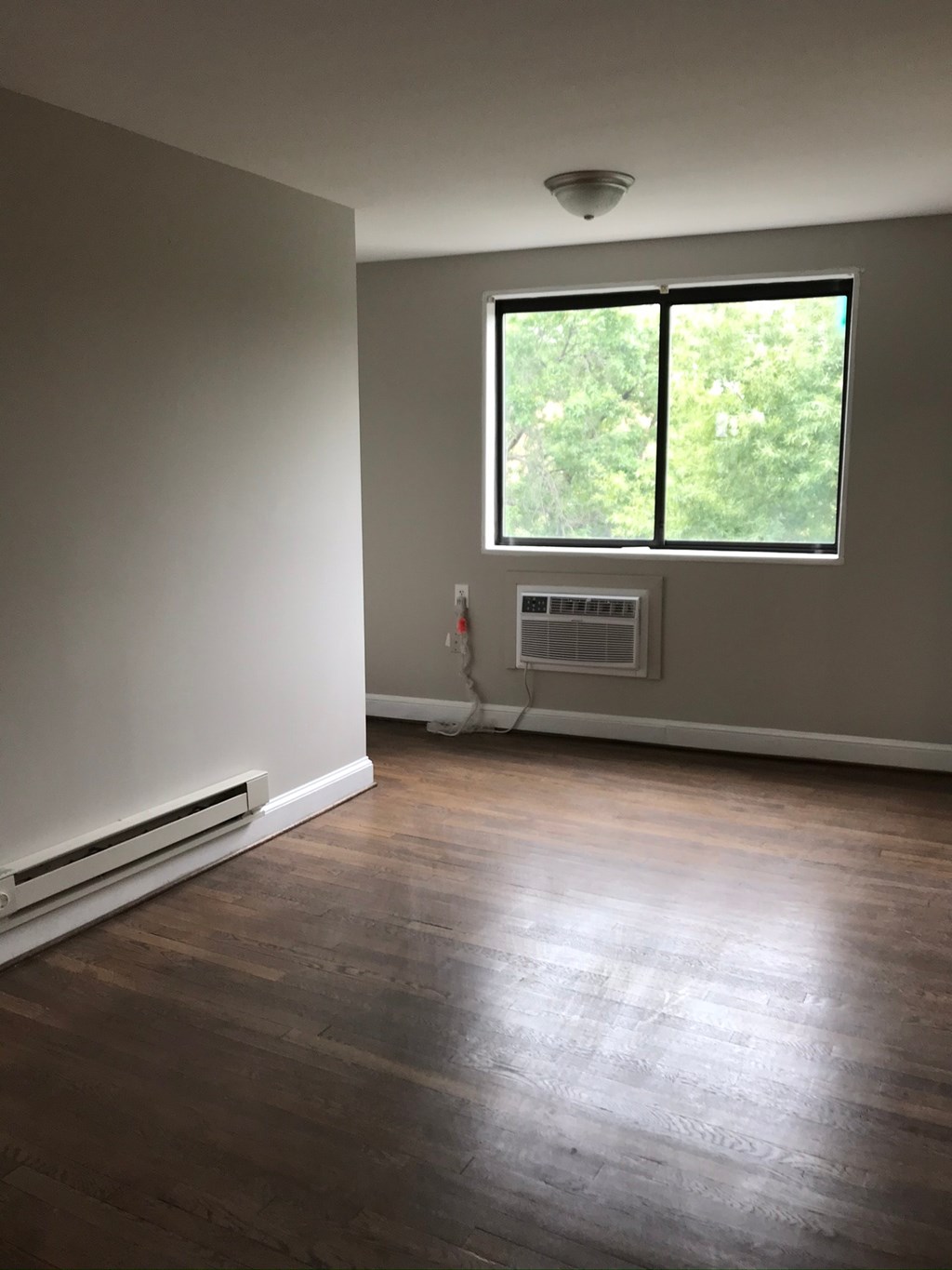 an empty living room with a window and wood floors