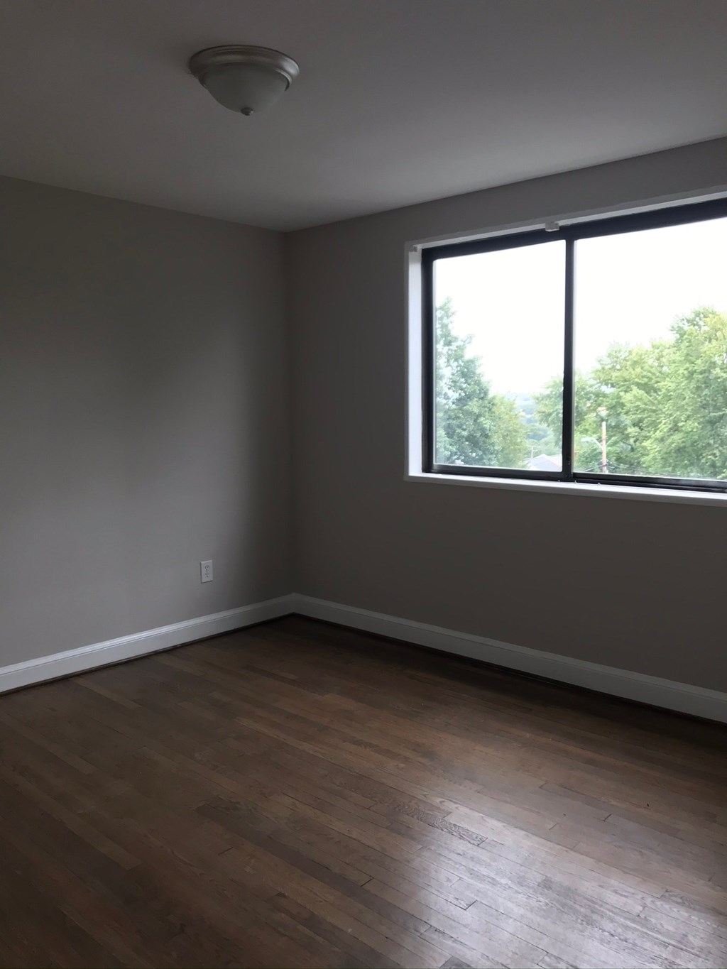 an empty room with a large window and wooden floors