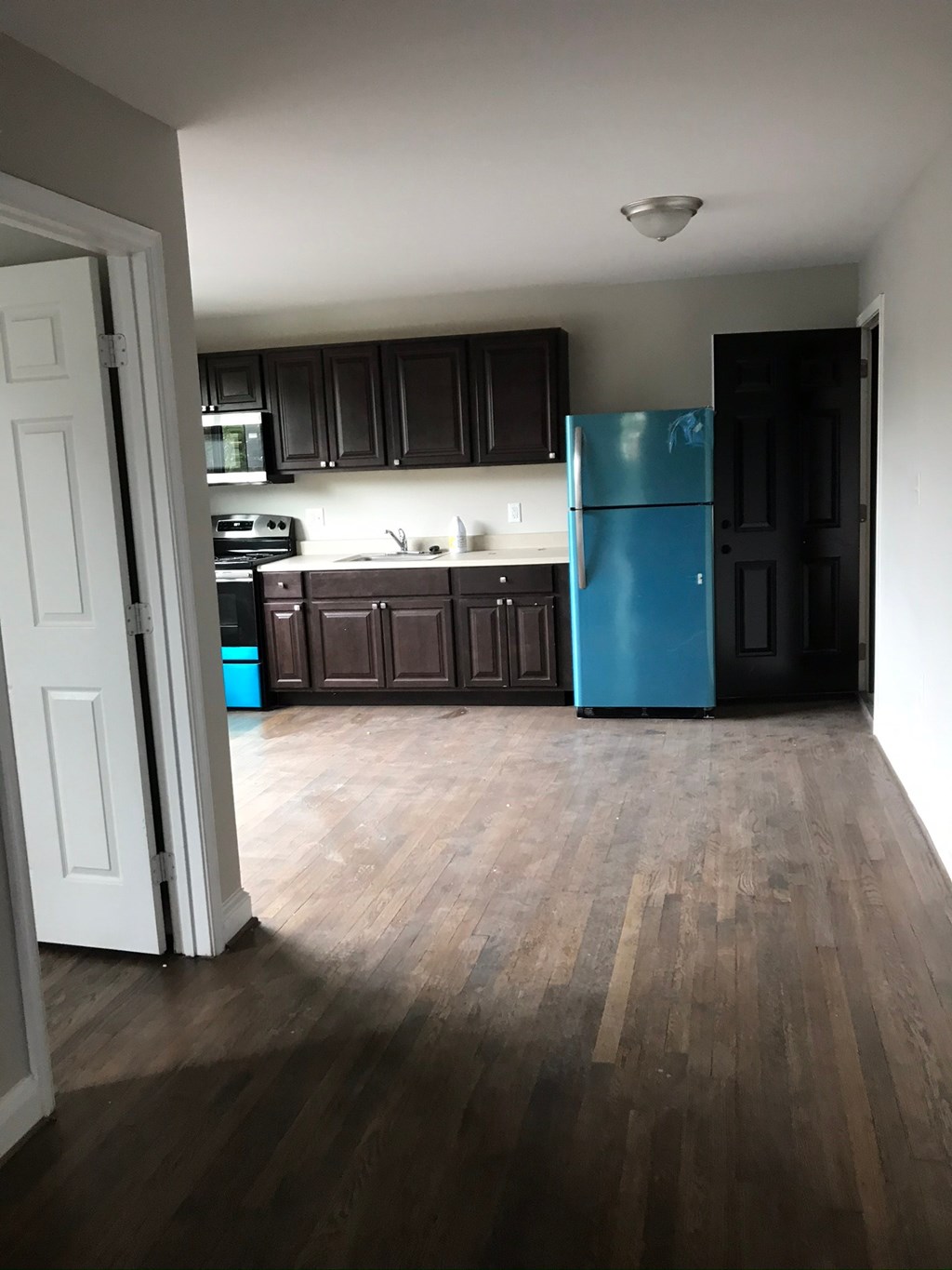 an empty kitchen with dark cabinets and a blue refrigerator