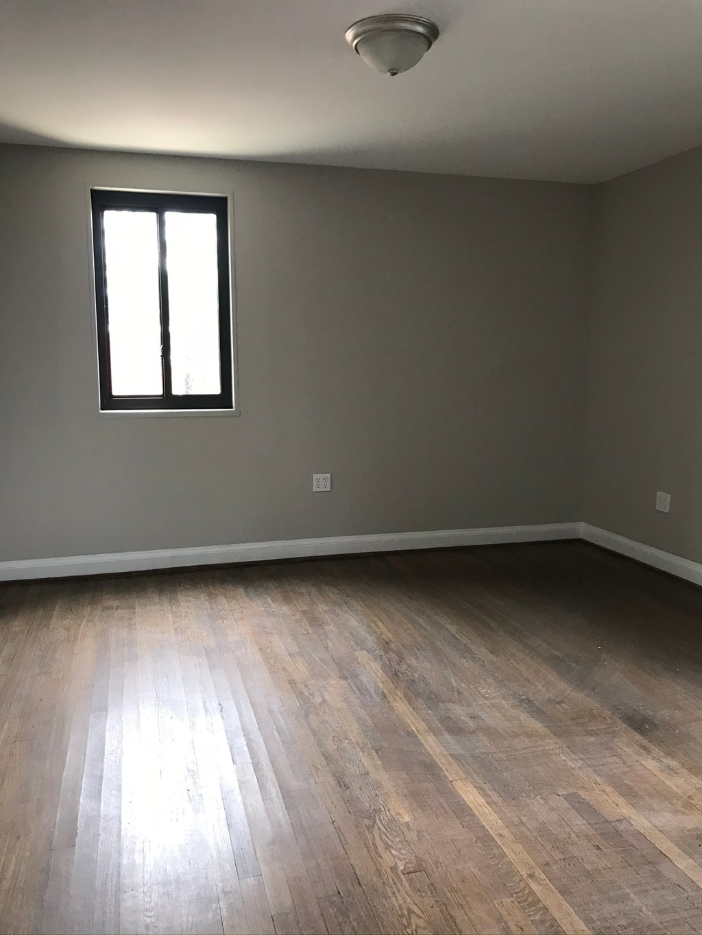 an empty room with wooden floors and a window