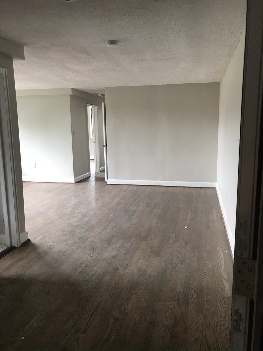 an empty living room with white walls and wooden floors