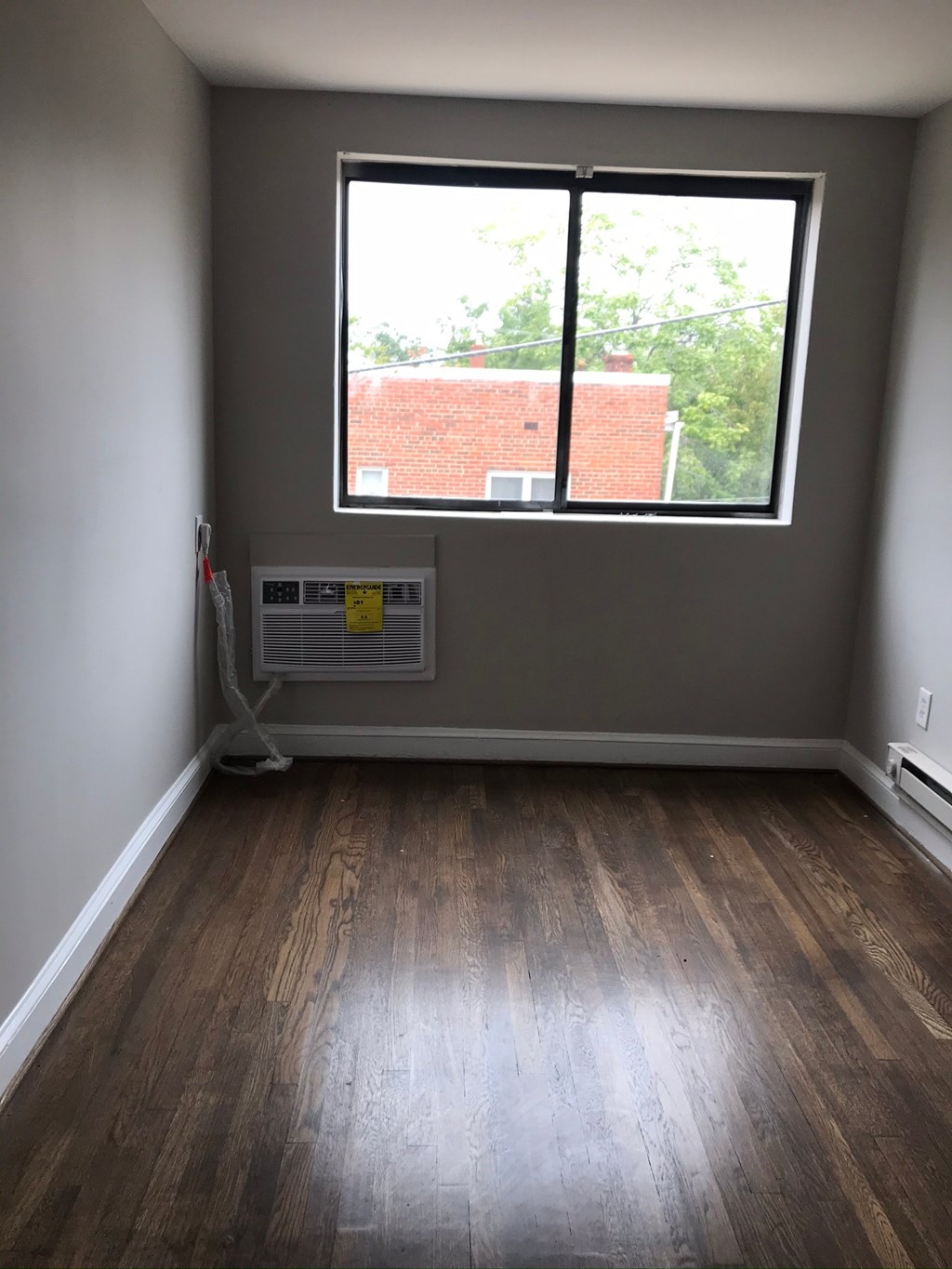 an empty room with a window and wooden floors
