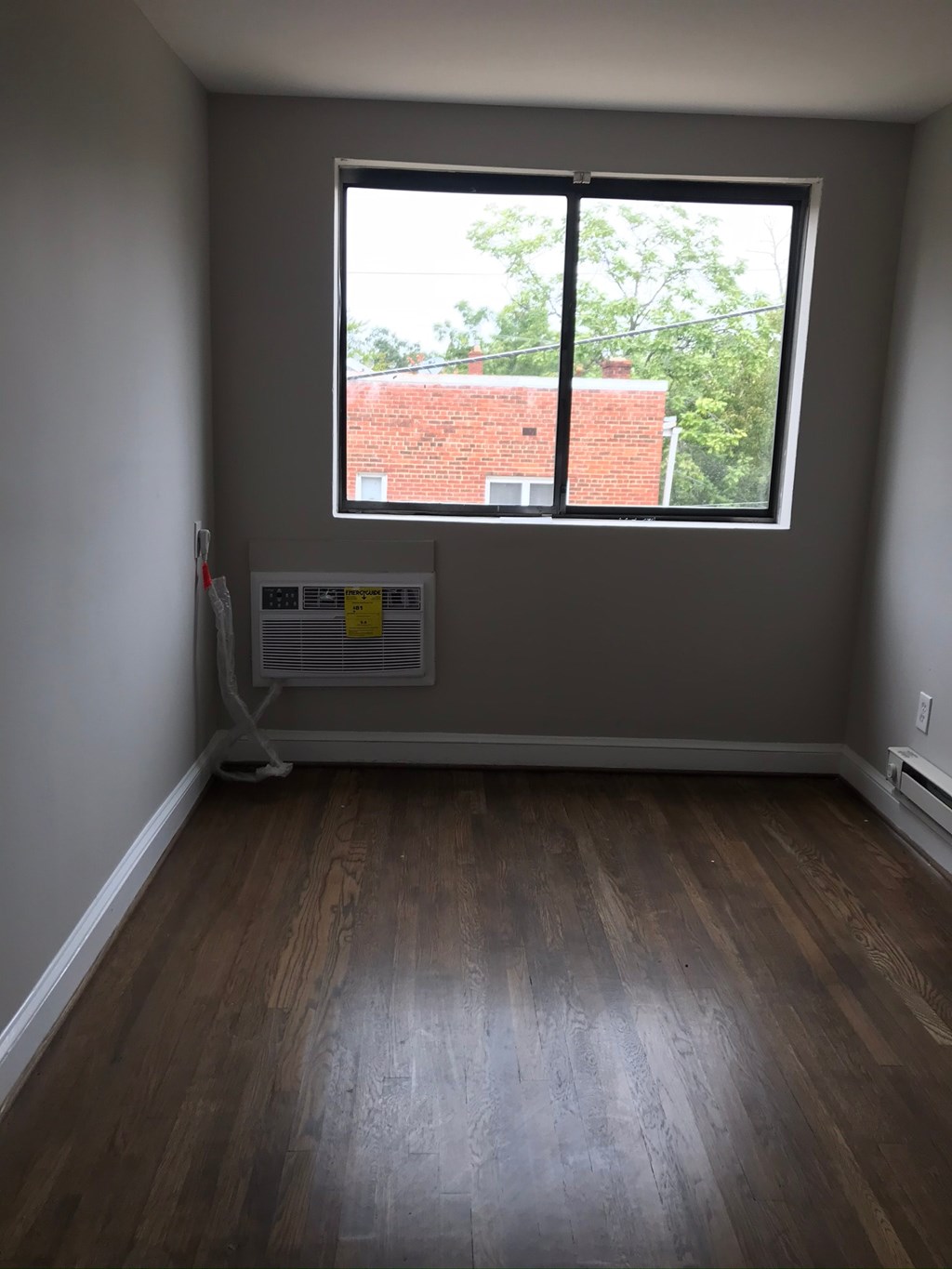 an empty room with a window and wooden floors