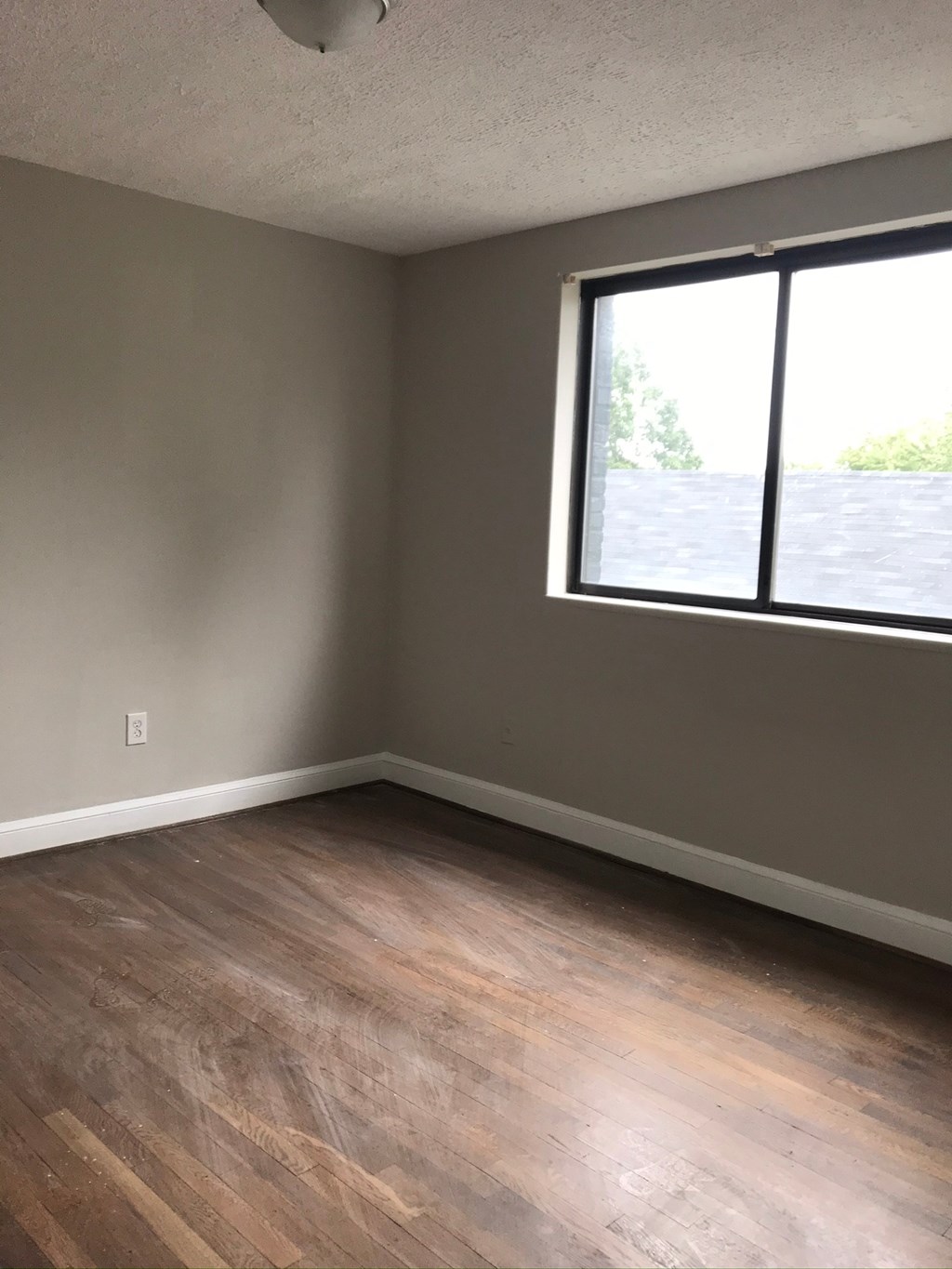 an empty room with a large window and wooden floors