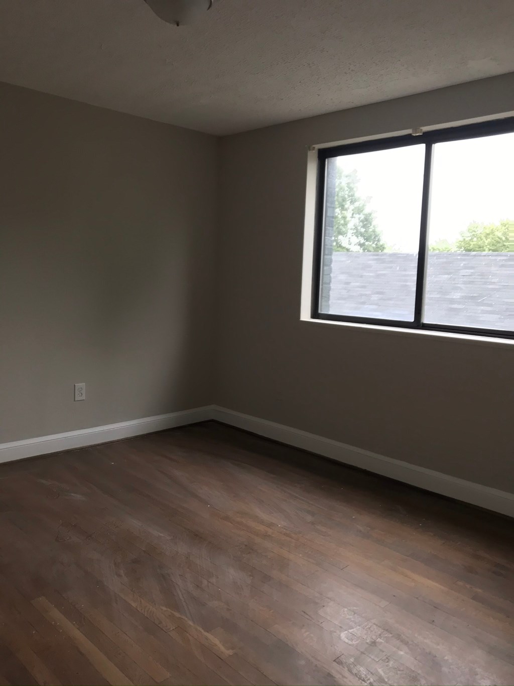 an empty room with a window and wooden floors