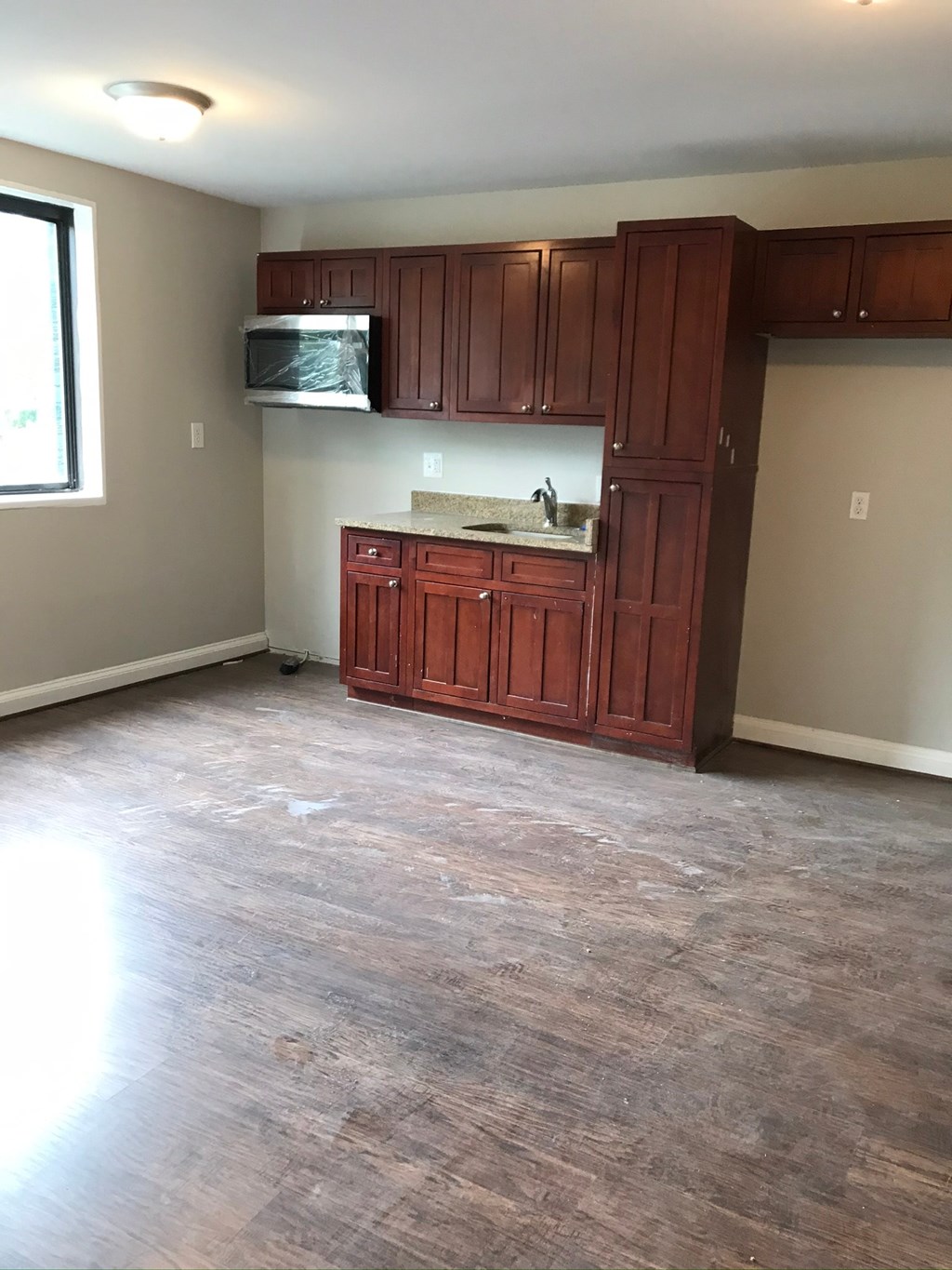 an empty living room with wooden floors and cabinets