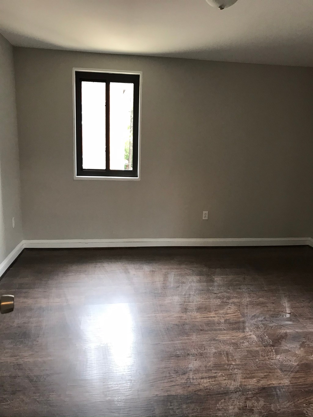 an empty living room with wood floors and a window