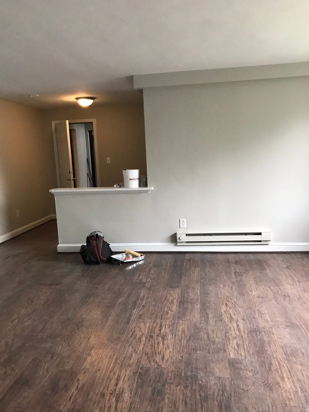 an empty living room with a white wall and wood floors