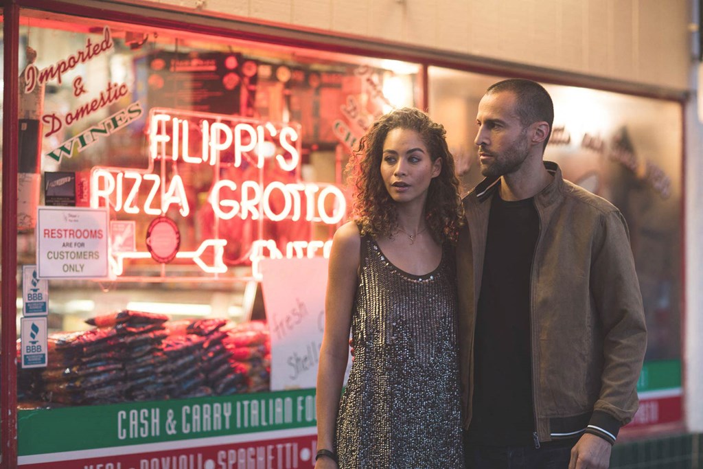 a man and a woman standing in front of a restaurant