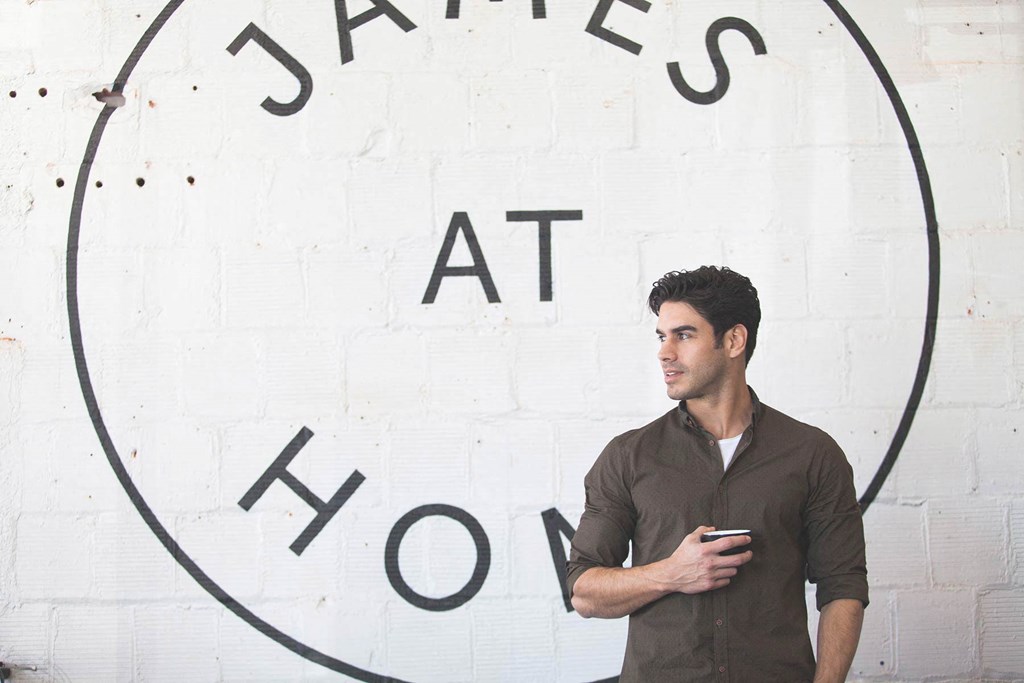 a man standing in front of a wall holding a cell phone