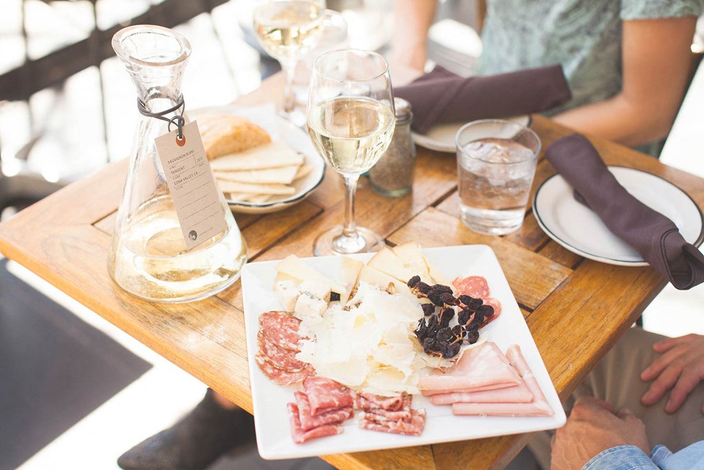 a wooden table with a plate of food and glasses of wine