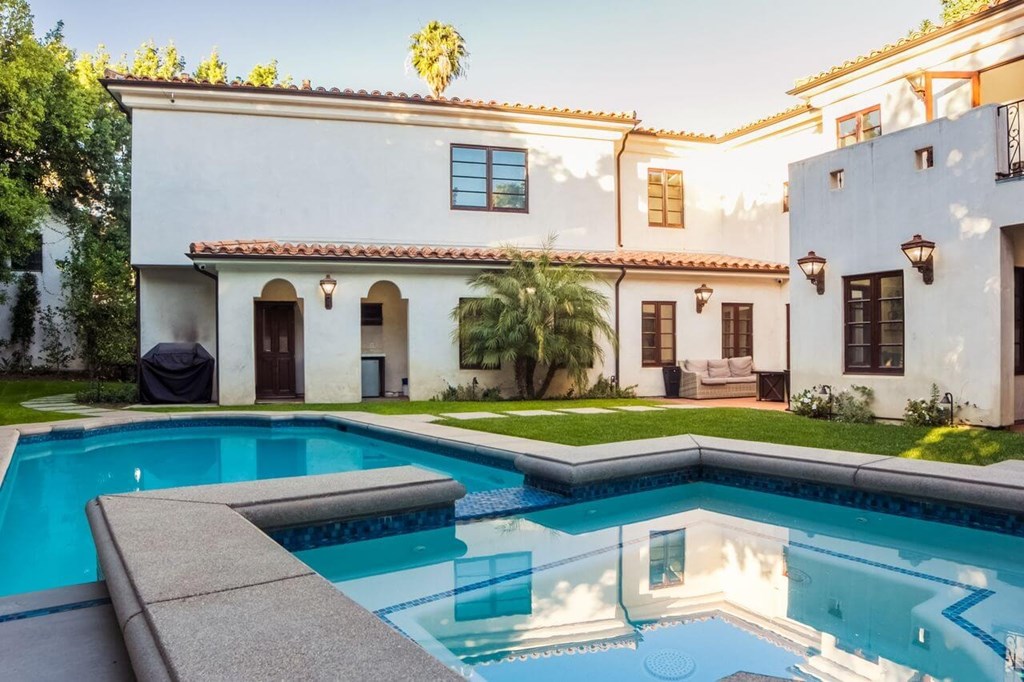 the pool is in front of a white house with a swimming pool