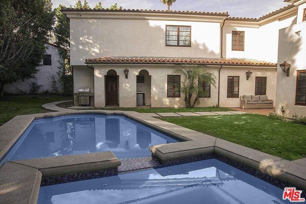 a swimming pool in front of a house with a courtyard