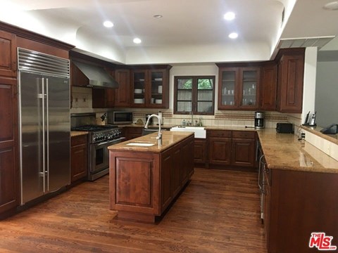 a large kitchen with wooden cabinets and stainless steel appliances