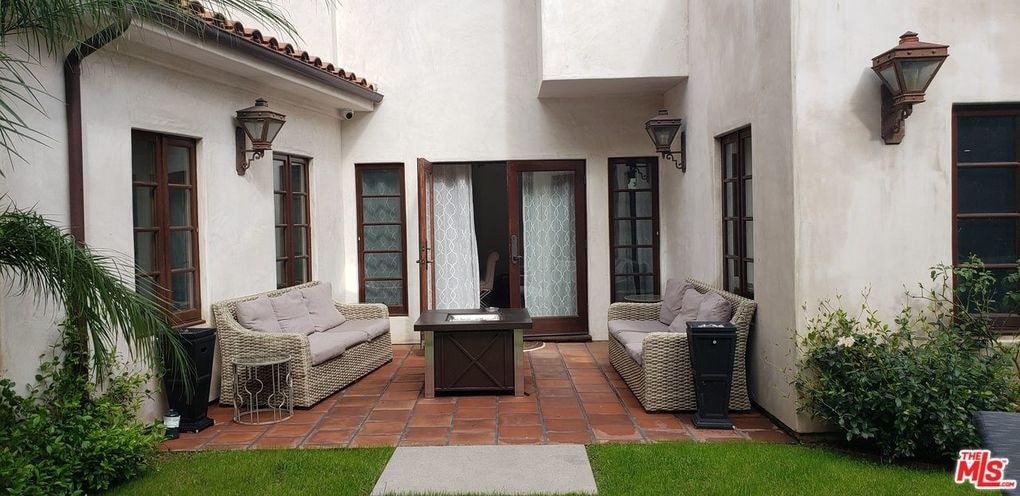 a patio with chairs and a table in front of a house