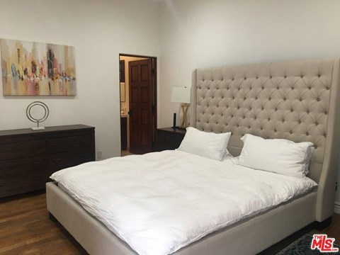 a bedroom with a bed and a dresser and a painting