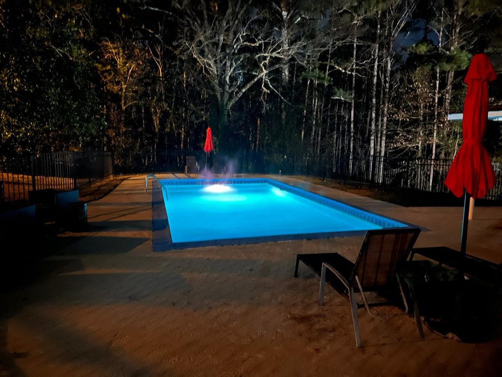 the pool is lit up at night with sprinklers