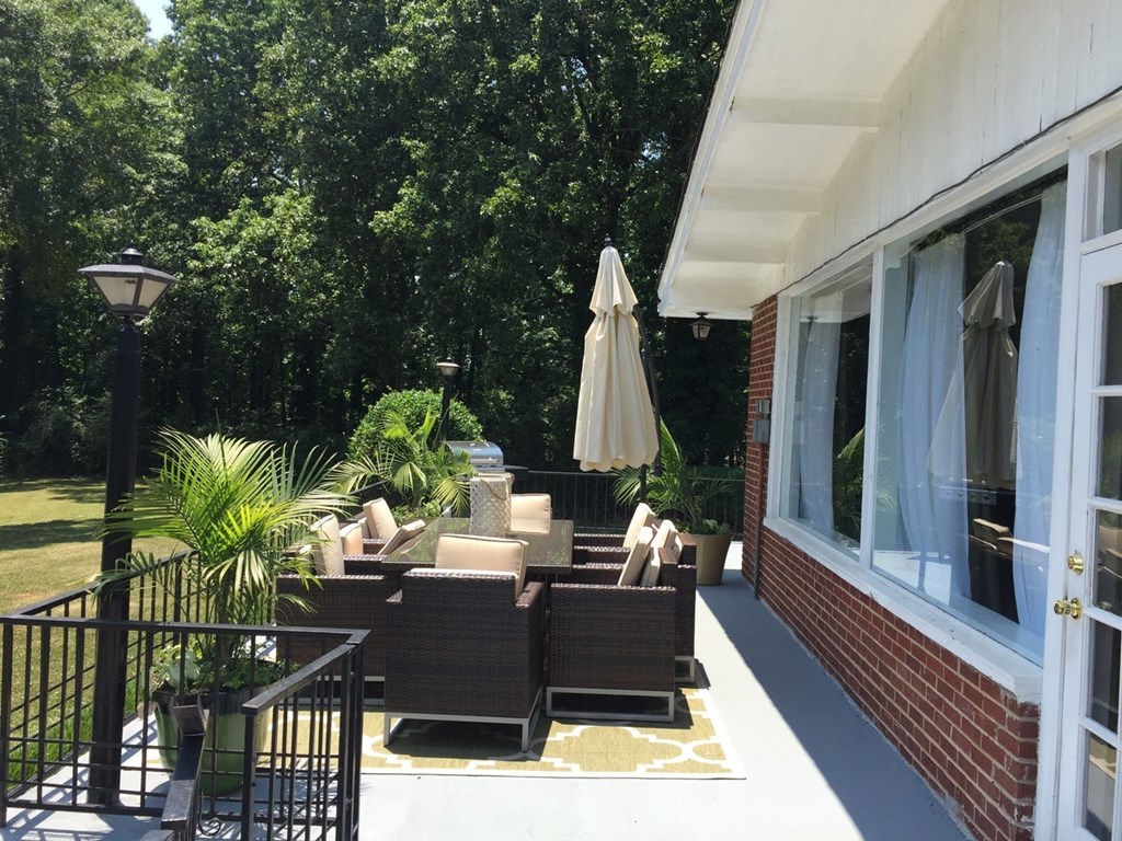 a patio with chairs and an umbrella outside of a house