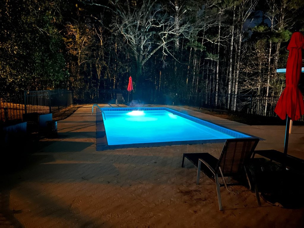 the pool is lit up at night with a blue light in it