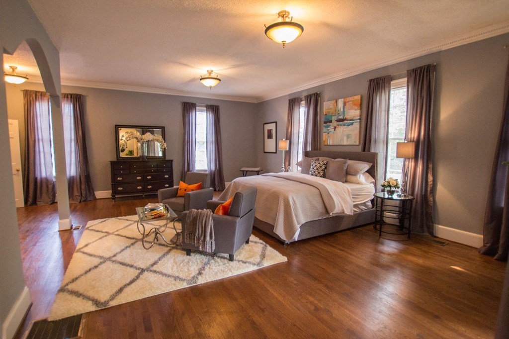 a master bedroom with a large bed and a couch and a chair