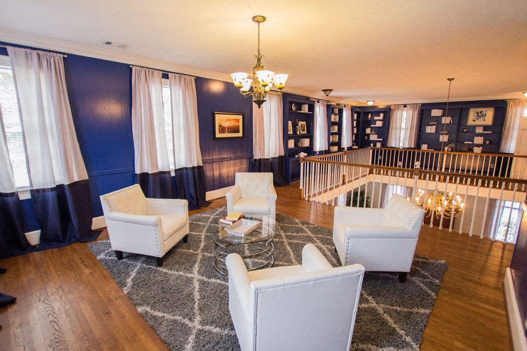 a living room with white chairs and a chandelier