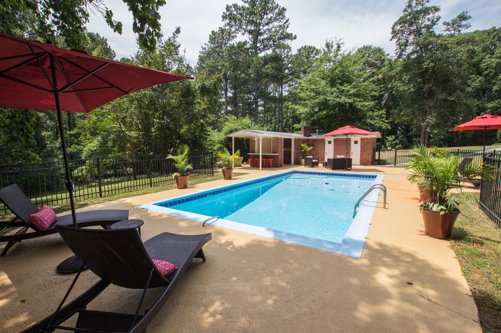 a swimming pool in a backyard with chairs and umbrellas