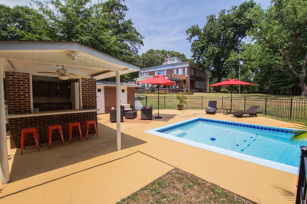our apartments have a pool and a patio with chairs and a bar