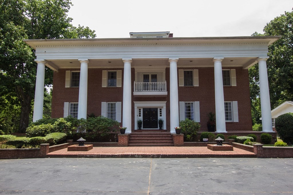 the front of a large brick house with columns