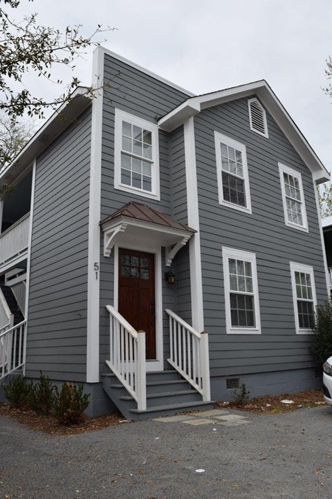 the front of a gray house with a wooden door