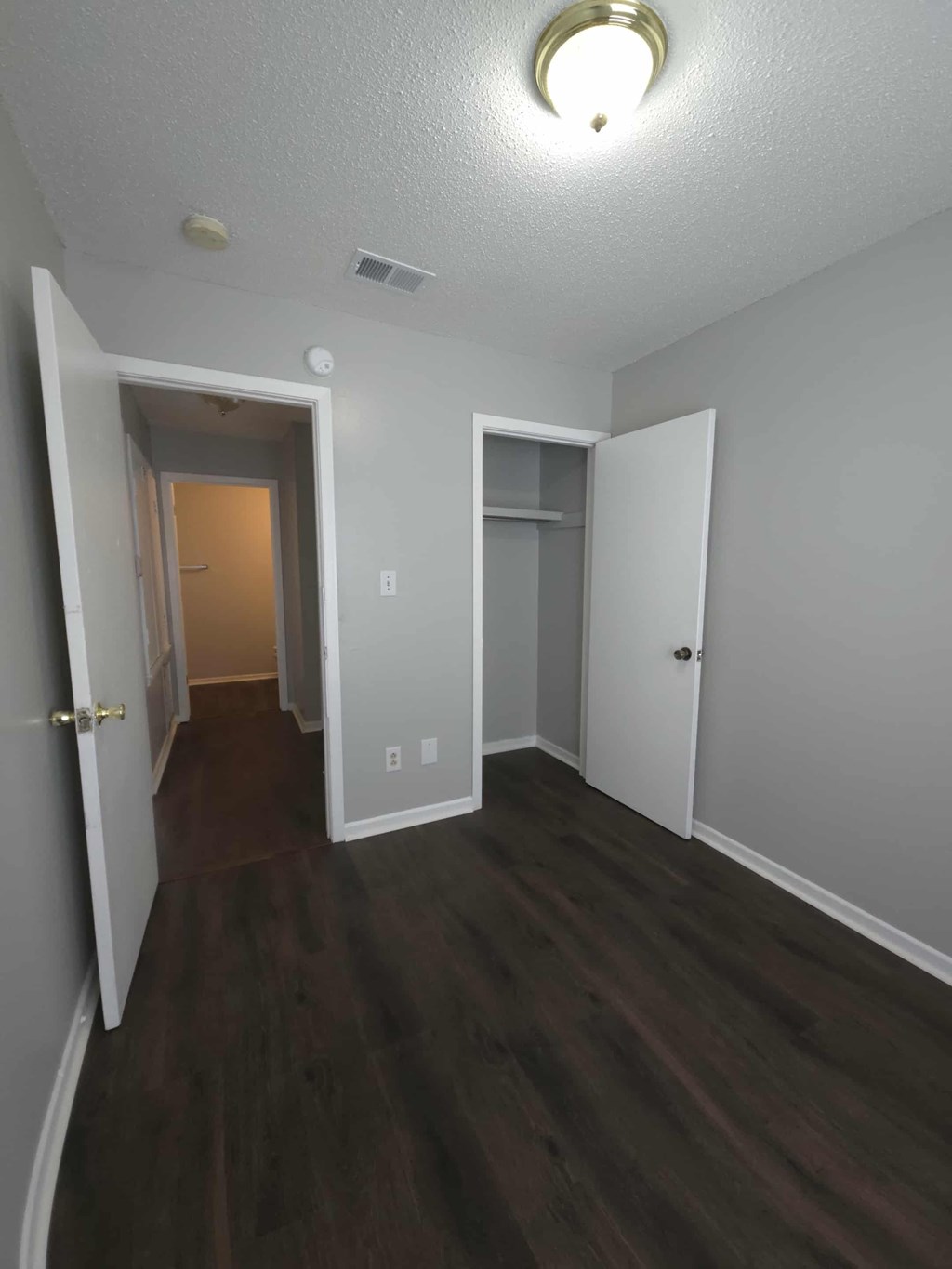 A hallway with a white door and a brown floor.
