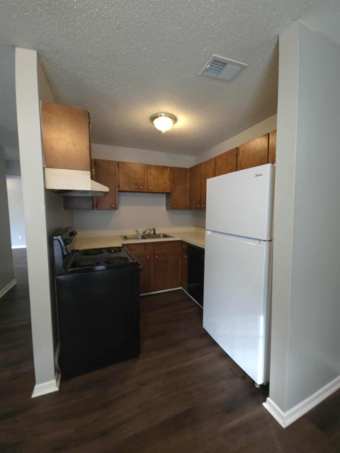 A kitchen with a white refrigerator and wooden cabinets.