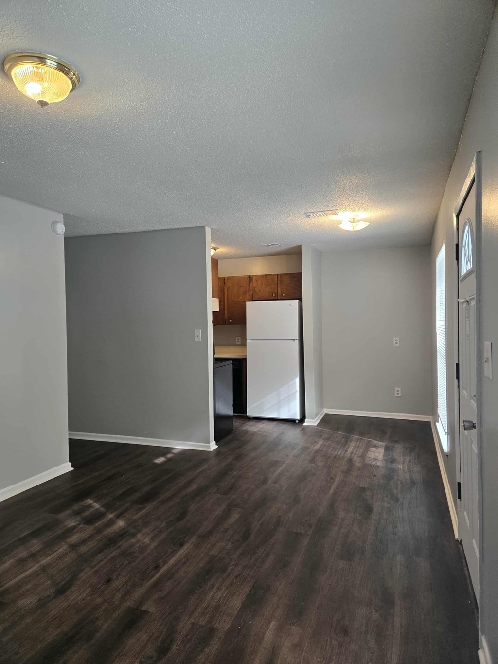 A kitchen area with a refrigerator and a door leading to another room.