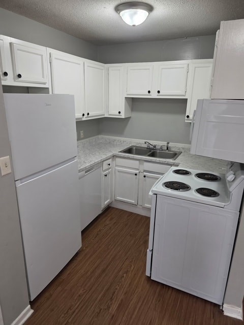A small white kitchen with wood floors and white appliances.
