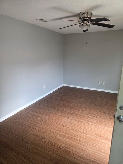 A room with a ceiling fan and wooden flooring.