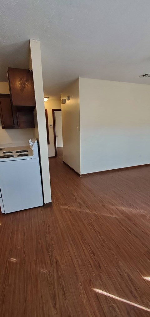 A kitchen with white appliances and wooden floors.