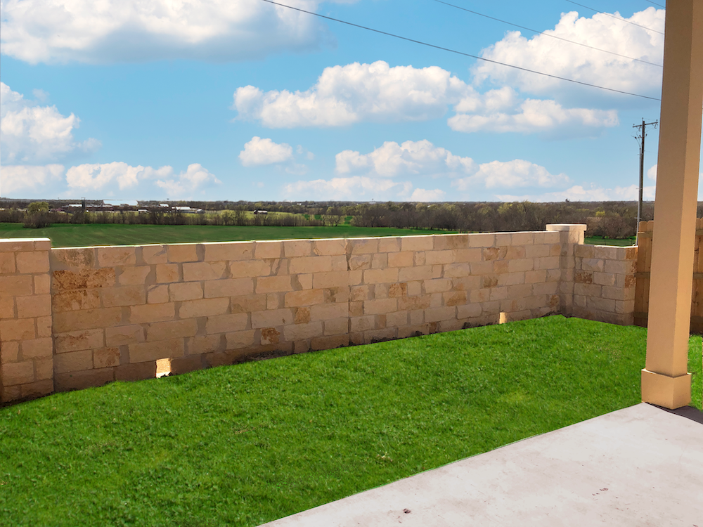 A wall made of bricks with a grassy area in front.