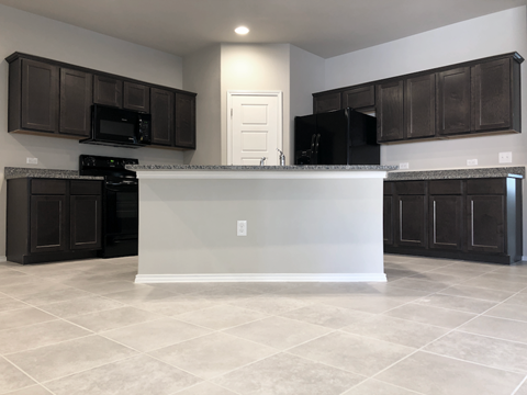 A kitchen with black cabinets and a white island.