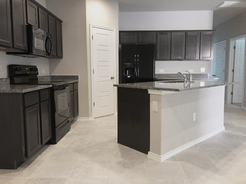 A kitchen with black cabinets and a black refrigerator.