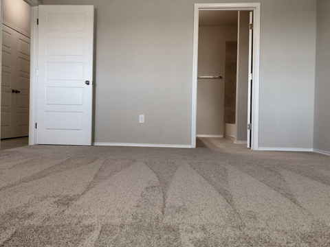 A carpeted room with two doors, one of which is open.