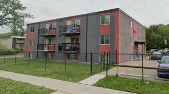 an apartment building with a chain link fence in front of it