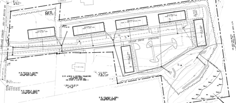 A black and white architectural plan shows a building with a parking lot in front.