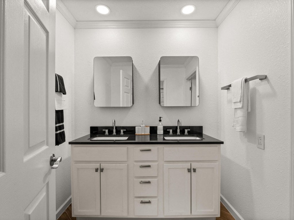 a white bathroom with two sinks and two mirrors