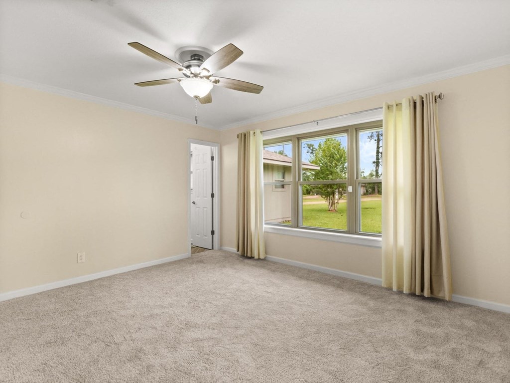 an empty living room with a ceiling fan and a window