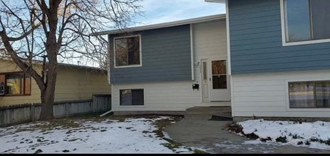 a white and blue house with snow on the ground